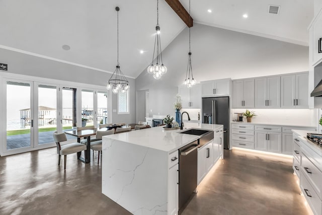 kitchen featuring appliances with stainless steel finishes, beam ceiling, decorative light fixtures, high vaulted ceiling, and an island with sink