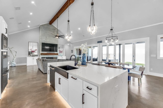 kitchen with a center island with sink, white cabinets, sink, hanging light fixtures, and light stone counters