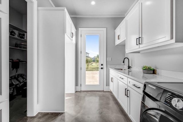 clothes washing area featuring cabinets and sink