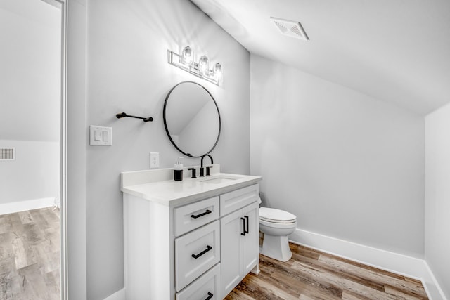 bathroom featuring toilet, vanity, vaulted ceiling, and hardwood / wood-style flooring