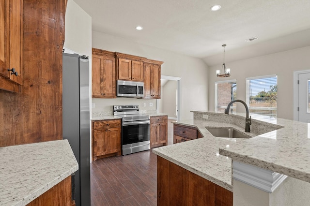 kitchen featuring dark hardwood / wood-style floors, hanging light fixtures, sink, appliances with stainless steel finishes, and light stone counters