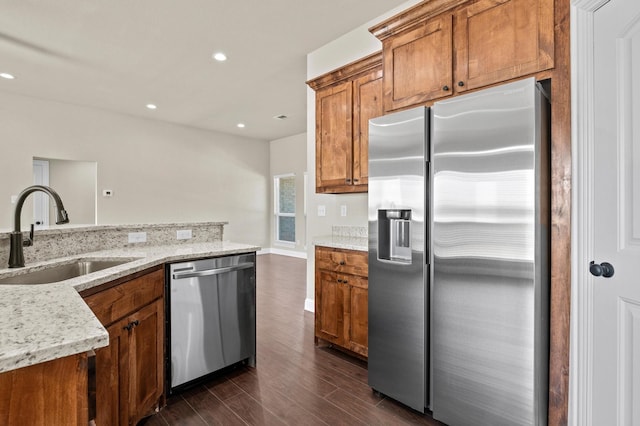 kitchen featuring light stone countertops, sink, stainless steel appliances, a wealth of natural light, and dark wood-type flooring