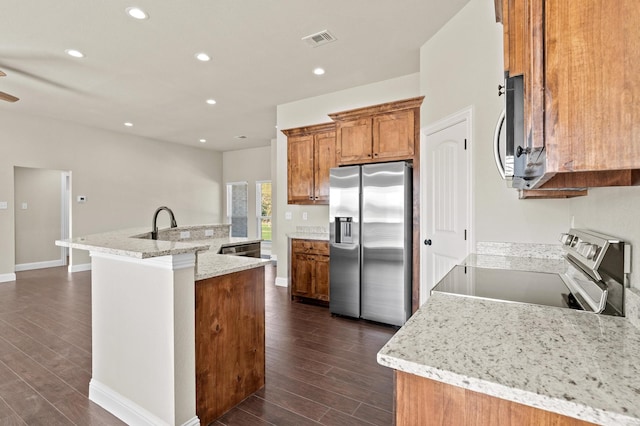 kitchen featuring stainless steel appliances, light stone countertops, dark hardwood / wood-style flooring, and a kitchen island with sink