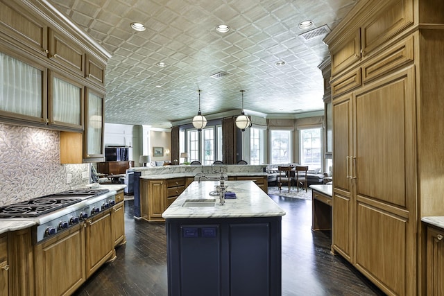 5804 Indianwood Ln, Fort Worth, TX 76132 - kitchen with stainless steel gas cooktop, an ornate ceiling, a center island with sink, decorative backsplash, and brown cabinets