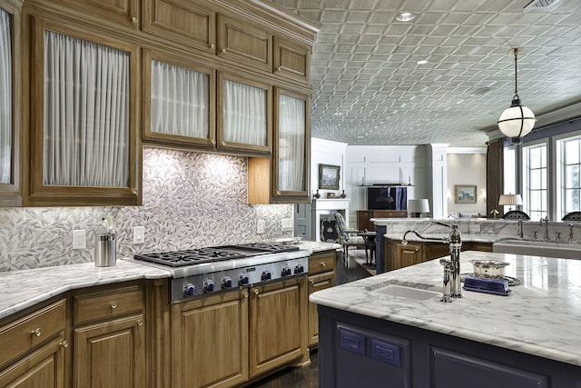 5804 Indianwood Ln, Fort Worth, TX 76132 - kitchen featuring light stone counters, stainless steel gas stovetop, brown cabinets, open floor plan, and backsplash