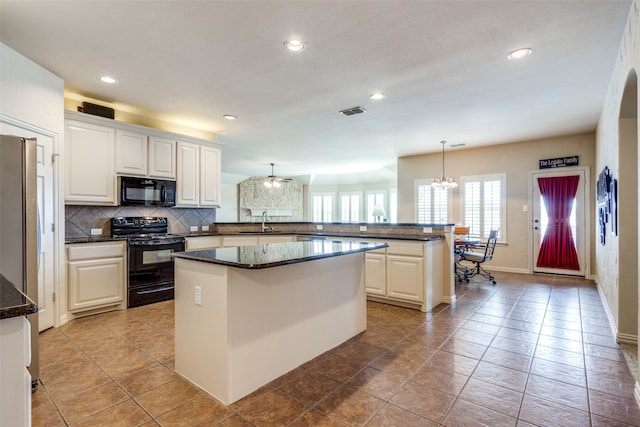 kitchen with black appliances, white cabinets, kitchen peninsula, and pendant lighting