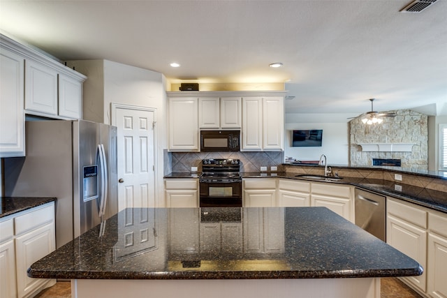 kitchen with dark stone countertops, sink, black appliances, a center island, and white cabinetry