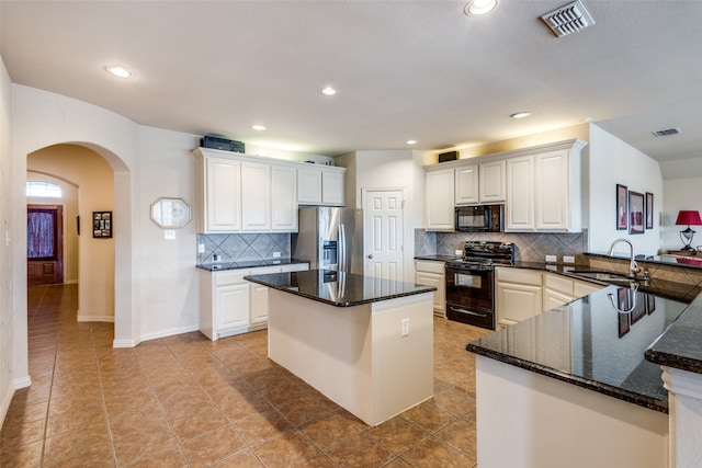 kitchen with backsplash, black appliances, sink, and white cabinets