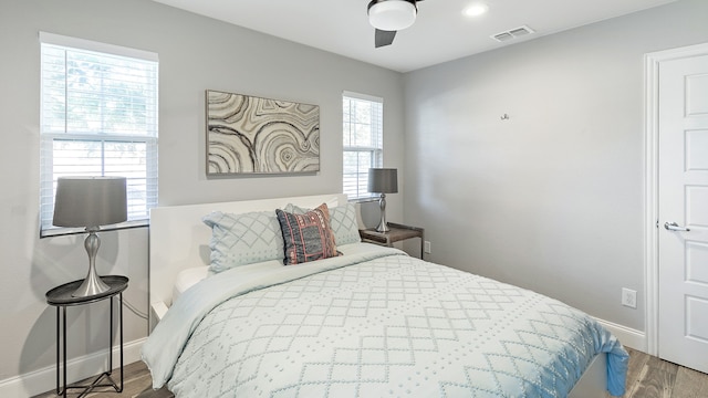 bedroom featuring multiple windows, hardwood / wood-style flooring, and ceiling fan