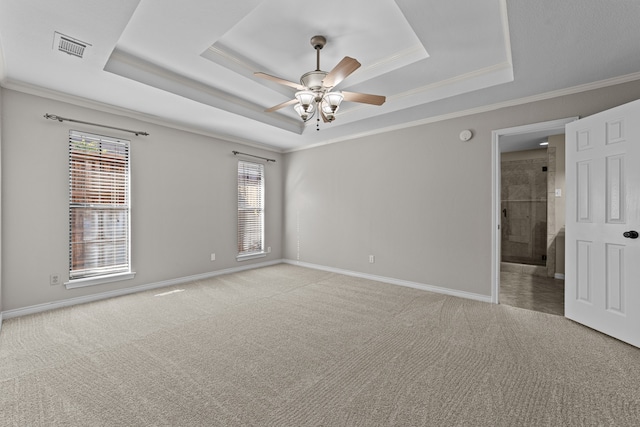 spare room with ceiling fan, a raised ceiling, ornamental molding, and light colored carpet