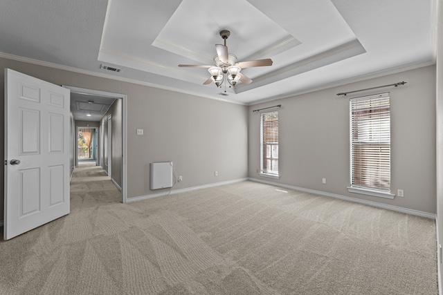 carpeted empty room with ceiling fan, a raised ceiling, and crown molding