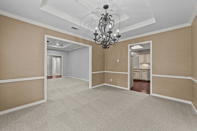 carpeted spare room featuring ornamental molding, a tray ceiling, and an inviting chandelier