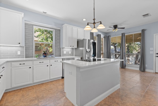 kitchen featuring white cabinets, black electric stovetop, and stainless steel fridge