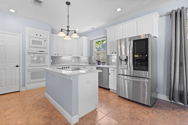 kitchen with a kitchen island, backsplash, white cabinetry, stainless steel appliances, and pendant lighting