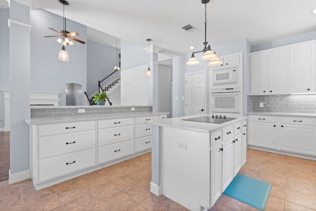 kitchen featuring kitchen peninsula, white cabinets, a kitchen island, backsplash, and white appliances