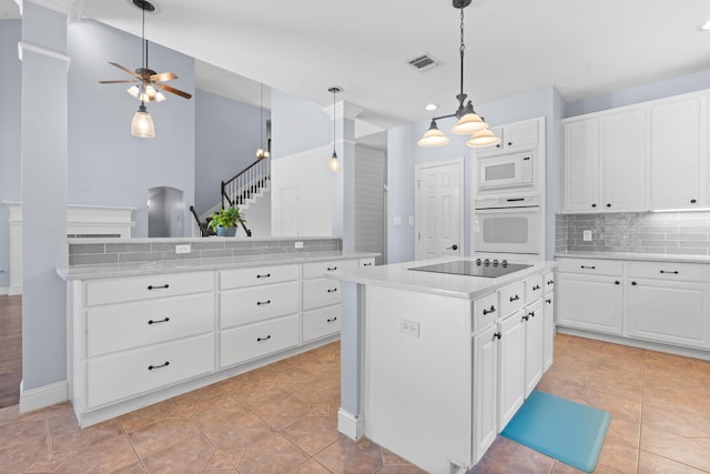 kitchen with tasteful backsplash, visible vents, light countertops, a center island, and white appliances