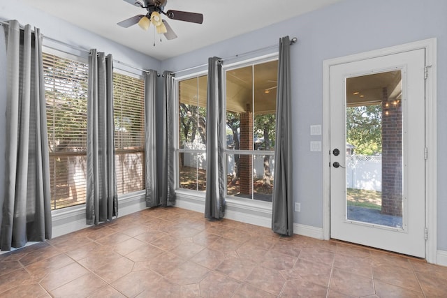 doorway with baseboards, ceiling fan, and tile patterned flooring