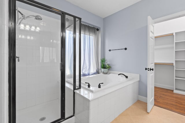 bathroom with a walk in closet, a shower stall, tile patterned flooring, and a bath