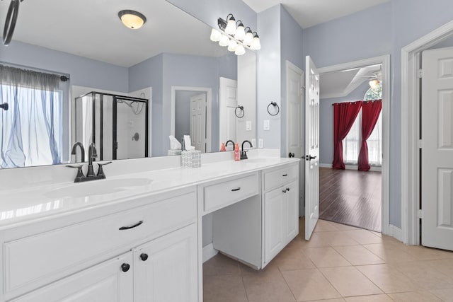 bathroom featuring double vanity, tile patterned flooring, a stall shower, and a sink