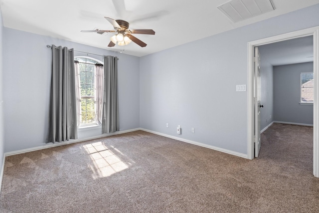 carpeted empty room featuring baseboards, visible vents, a wealth of natural light, and ceiling fan