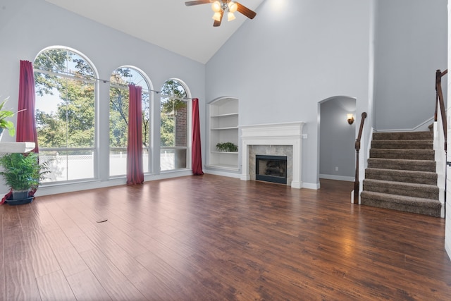 unfurnished living room featuring high vaulted ceiling, built in features, dark hardwood / wood-style flooring, and a tile fireplace