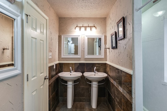 bathroom featuring a textured ceiling, tile patterned floors, and tile walls