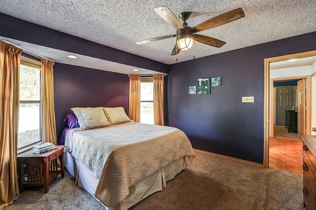 bedroom featuring ceiling fan, a textured ceiling, multiple windows, and carpet floors