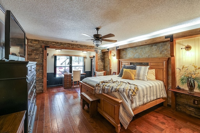 bedroom with ceiling fan, wood walls, a textured ceiling, and dark hardwood / wood-style flooring