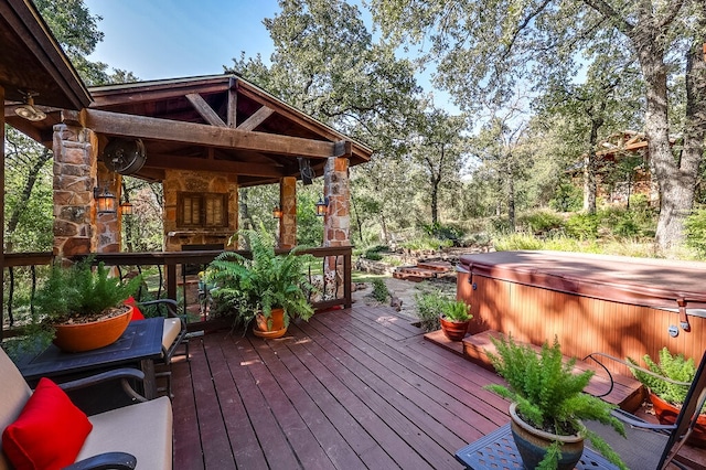 wooden terrace featuring a hot tub and a stone fireplace