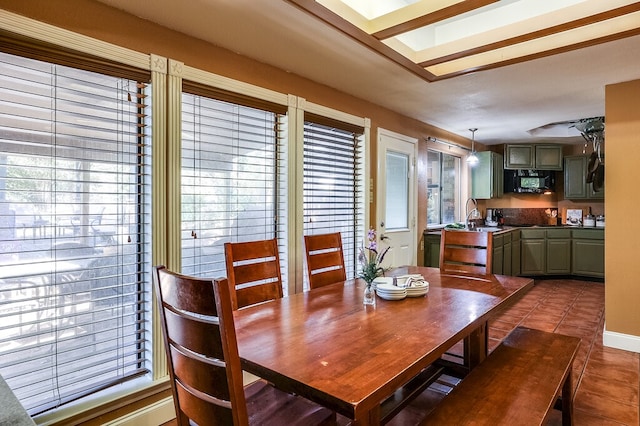 dining space with dark tile patterned flooring, a healthy amount of sunlight, a skylight, and sink