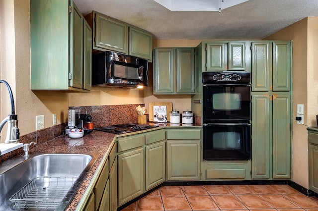 kitchen featuring a textured ceiling, light tile patterned flooring, black appliances, sink, and green cabinets