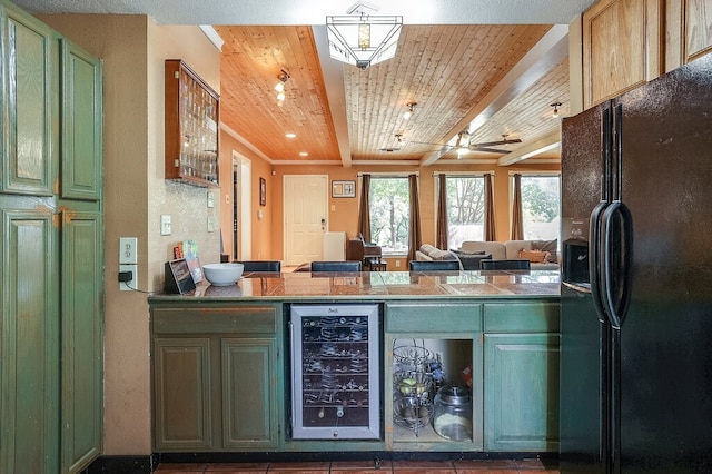 kitchen with green cabinets, black fridge, wooden ceiling, beamed ceiling, and beverage cooler