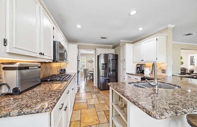 kitchen with appliances with stainless steel finishes, tasteful backsplash, sink, white cabinets, and kitchen peninsula