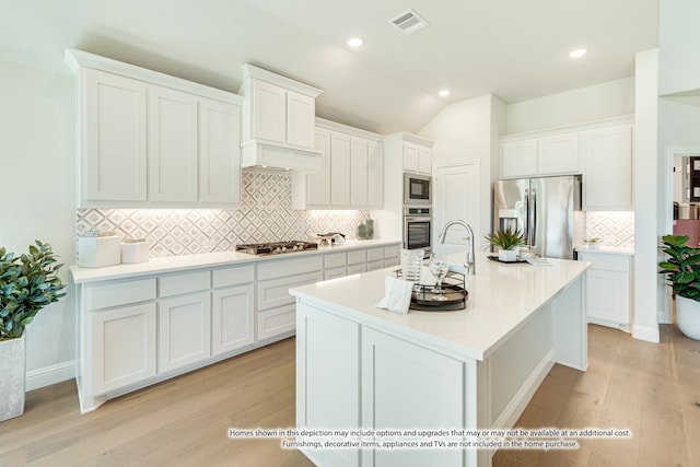 kitchen with decorative backsplash, appliances with stainless steel finishes, white cabinets, and light hardwood / wood-style floors