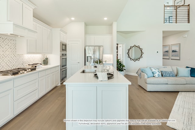 kitchen featuring stainless steel appliances, sink, an island with sink, and white cabinets