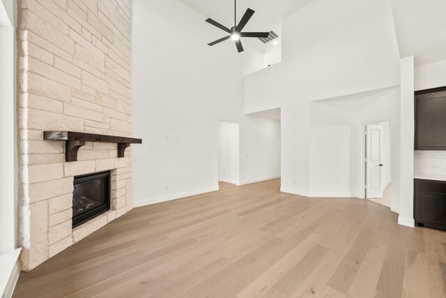 kitchen featuring a large fireplace, sink, an island with sink, and white cabinets