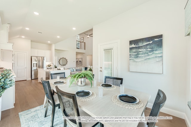 dining room featuring sink, ceiling fan, high vaulted ceiling, and light hardwood / wood-style flooring