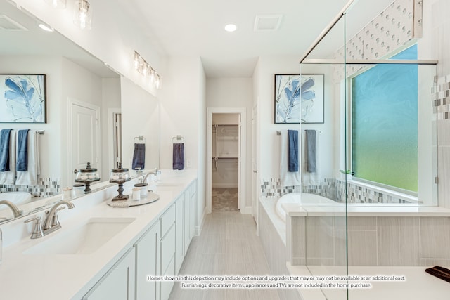 bathroom featuring vanity, tiled tub, and tile patterned flooring