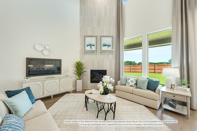 living room featuring hardwood / wood-style flooring, a high ceiling, and a fireplace