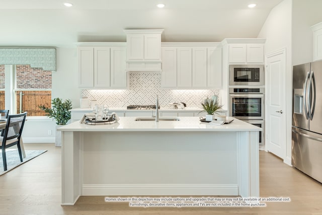 kitchen featuring appliances with stainless steel finishes, a kitchen island with sink, white cabinetry, and light hardwood / wood-style floors