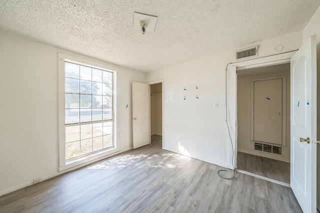 empty room with a textured ceiling and light wood-type flooring