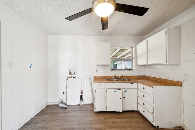 kitchen featuring hardwood / wood-style flooring, a textured ceiling, sink, and white cabinets