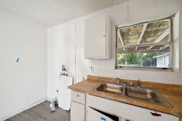 kitchen with wood walls, sink, a textured ceiling, hardwood / wood-style floors, and white cabinets