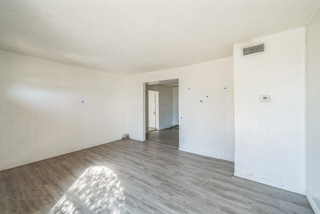 unfurnished room featuring light hardwood / wood-style floors and a textured ceiling