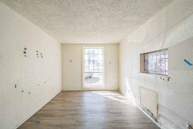 empty room featuring wood-type flooring and a textured ceiling