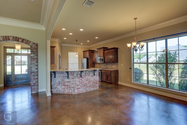 kitchen with hanging light fixtures, backsplash, a kitchen bar, ornamental molding, and stainless steel appliances