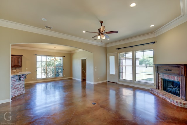 unfurnished living room with crown molding, a wealth of natural light, a brick fireplace, and ceiling fan with notable chandelier