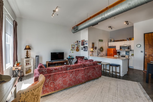 living room featuring sink, track lighting, and a towering ceiling