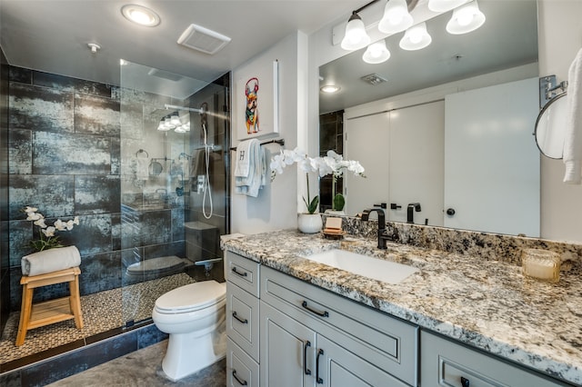 bathroom with a tile shower, toilet, and vanity