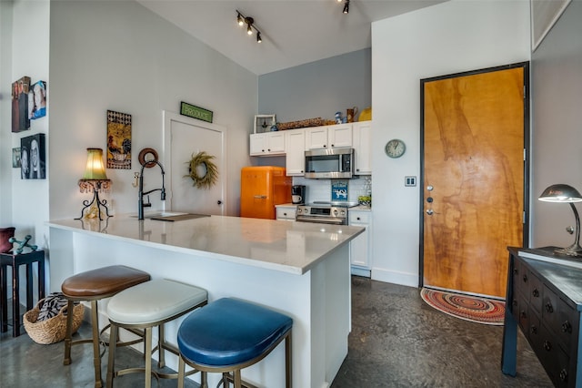 kitchen with appliances with stainless steel finishes, white cabinetry, backsplash, a kitchen breakfast bar, and kitchen peninsula